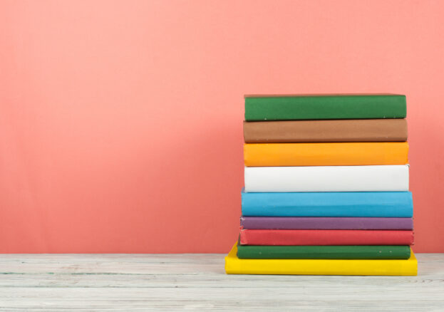 Book stack, hardback colorful books on wooden table and blue background. Back to school. Copy space for text. Education concept