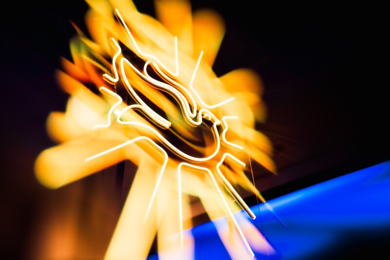 a yellow neon dove takes up the image, there is a blurred blue light in the background