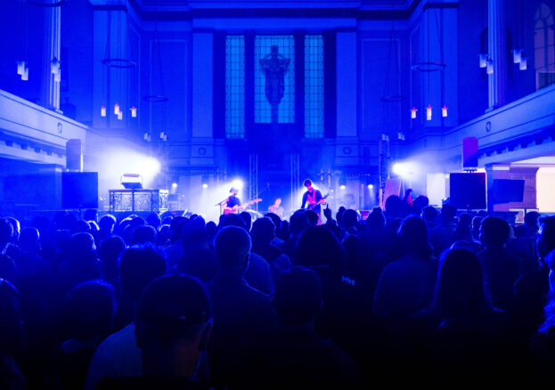 A crowd of people watching Honeyglaze at Sounds From The Other City 2023 in St Philips Church 