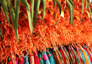 Highly textured green grasses, wiry orange threads and tassels stacked upon one another