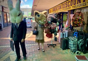 Two people shopping in Swinton Square wearing big animal heads. 