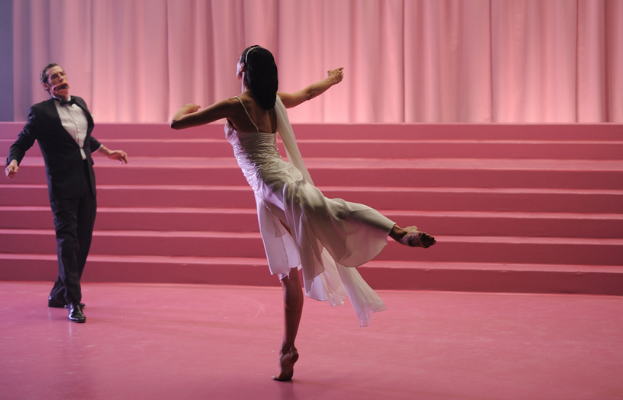 A man and woman dance in a pink theatre.