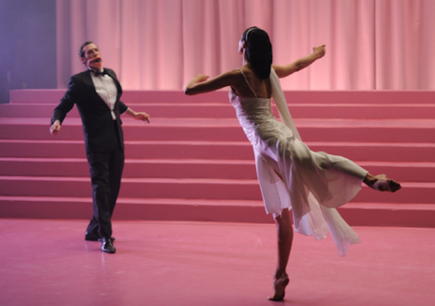 A man and woman dance in a pink theatre.