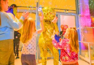 Two young girls dance with a human disco ball