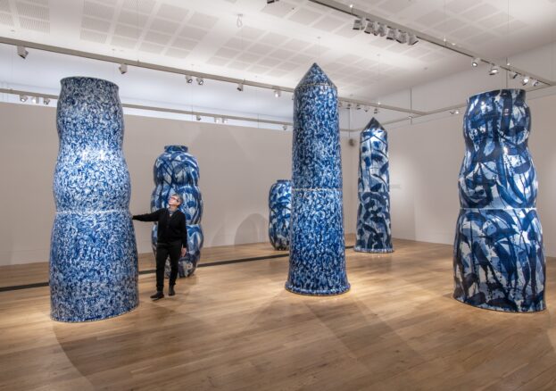Woman looking and touching large ceramic vessels