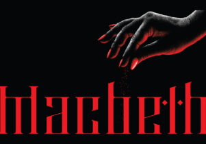 Macbeth at Hope Mill Theatre. Red writing spelling out 'Macbeth' with a black background. A mysterious hand in the top right corner sprinkling a substance onto the word Macbeth, lightened up by the red light the word Macbeth gives off.