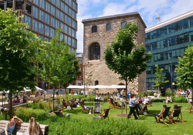 People relaxing outside, visiting a market and enjoying greenery by offices in the city.