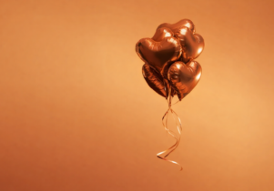 An orange background with dark orange balloons in the shape of hearts.