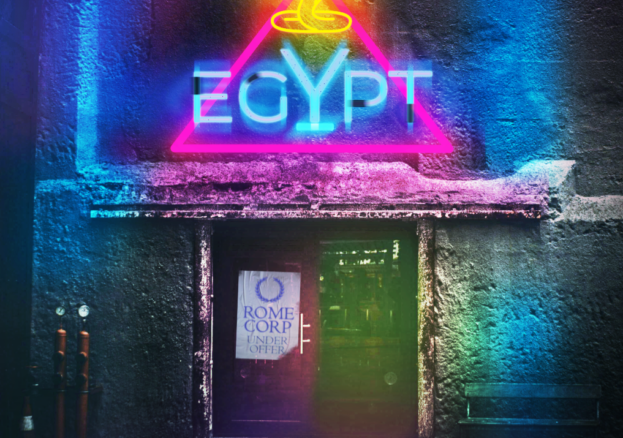 An image of a night club door with a pink and blue neon sign above it. The sign says Egypt with a gold neon cobra above it. On the club door is a sign saying Rome Corp - Under Offer
