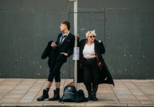 Two goths standing at a bus stop