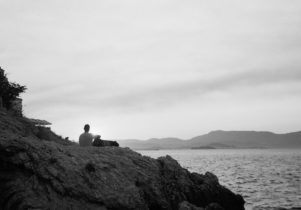 black and white image of person sitting on rock